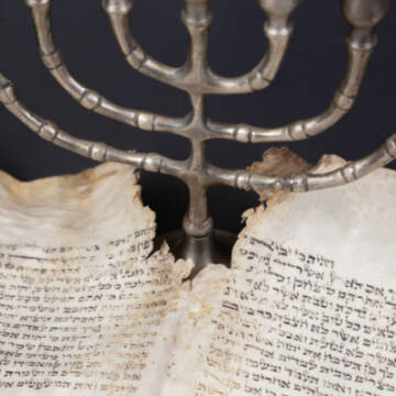 Grafika przedstawia menorę oraz fragment pisma świętego w Jidysz