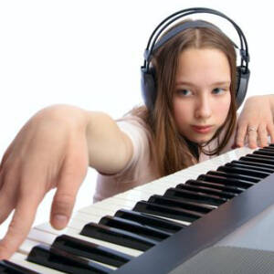 Grafika przedstawia nastolatkę w słuchawkach grającą na keyboardzie