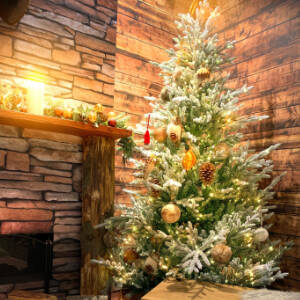 Grafika przedstawia rozświetloną choinkę umieszczoną w rogu salonu z kominkiem