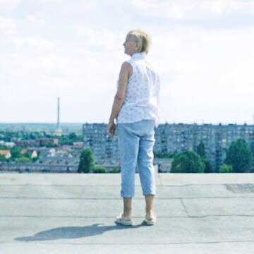 Grafika przedstawia kobietę stojącą na dachu budynku