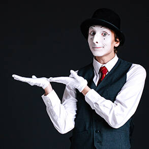 Grafika przedstawia mima z białą twarzą w czarnym kapeluszu