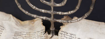 Zdjęcie przedstawia fragment pisma w języku jidysz oraz menorę